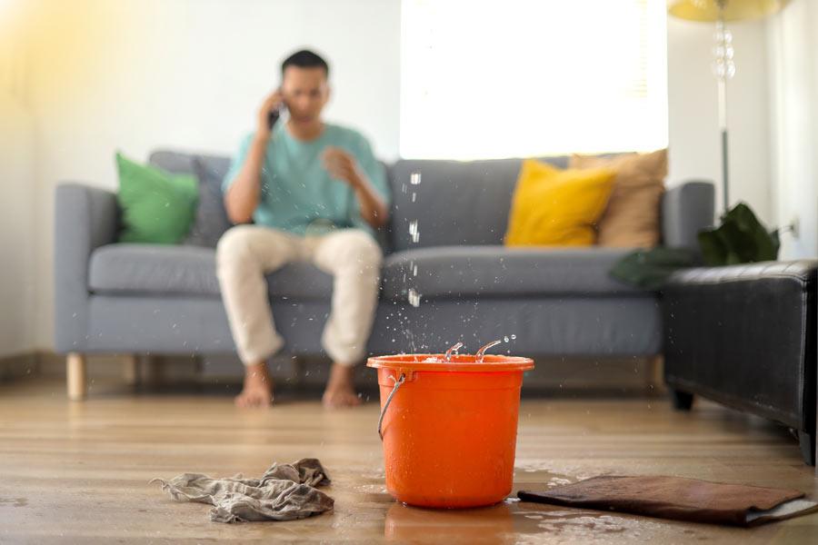 Bucket catching water from a ceiling leak in a living room